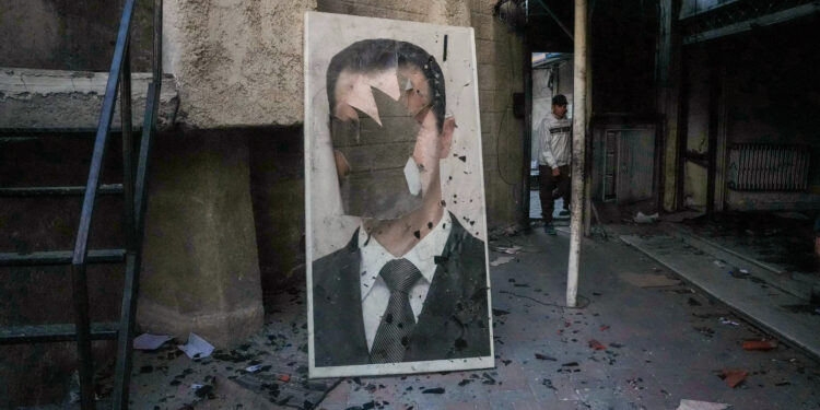 A defaced portrait of ousted Syrian president Bashar al-Assad stands in a ransacked government security facility, in Damascus, on December 8, 2024. (Photo by Rami al SAYED / AFP)